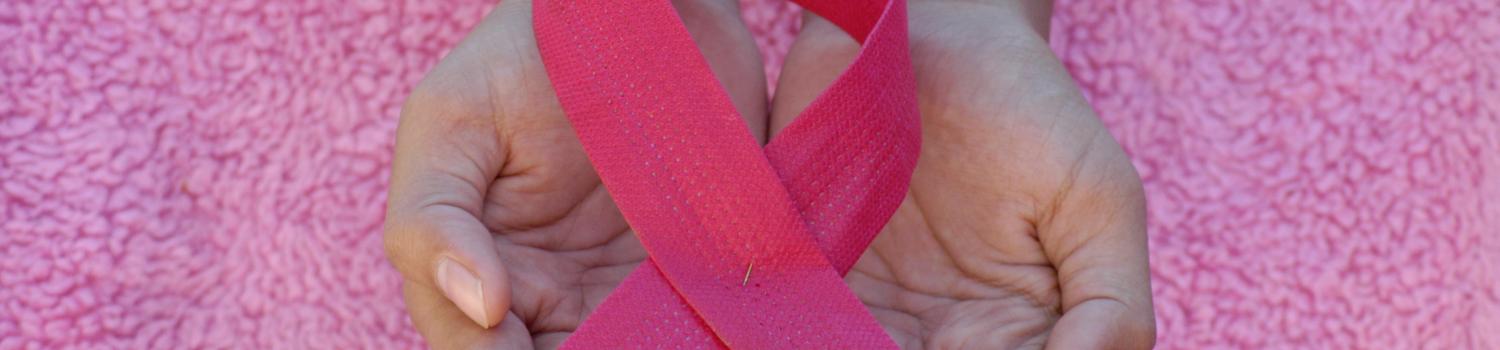 a pair of hands holding a pink ribbon 